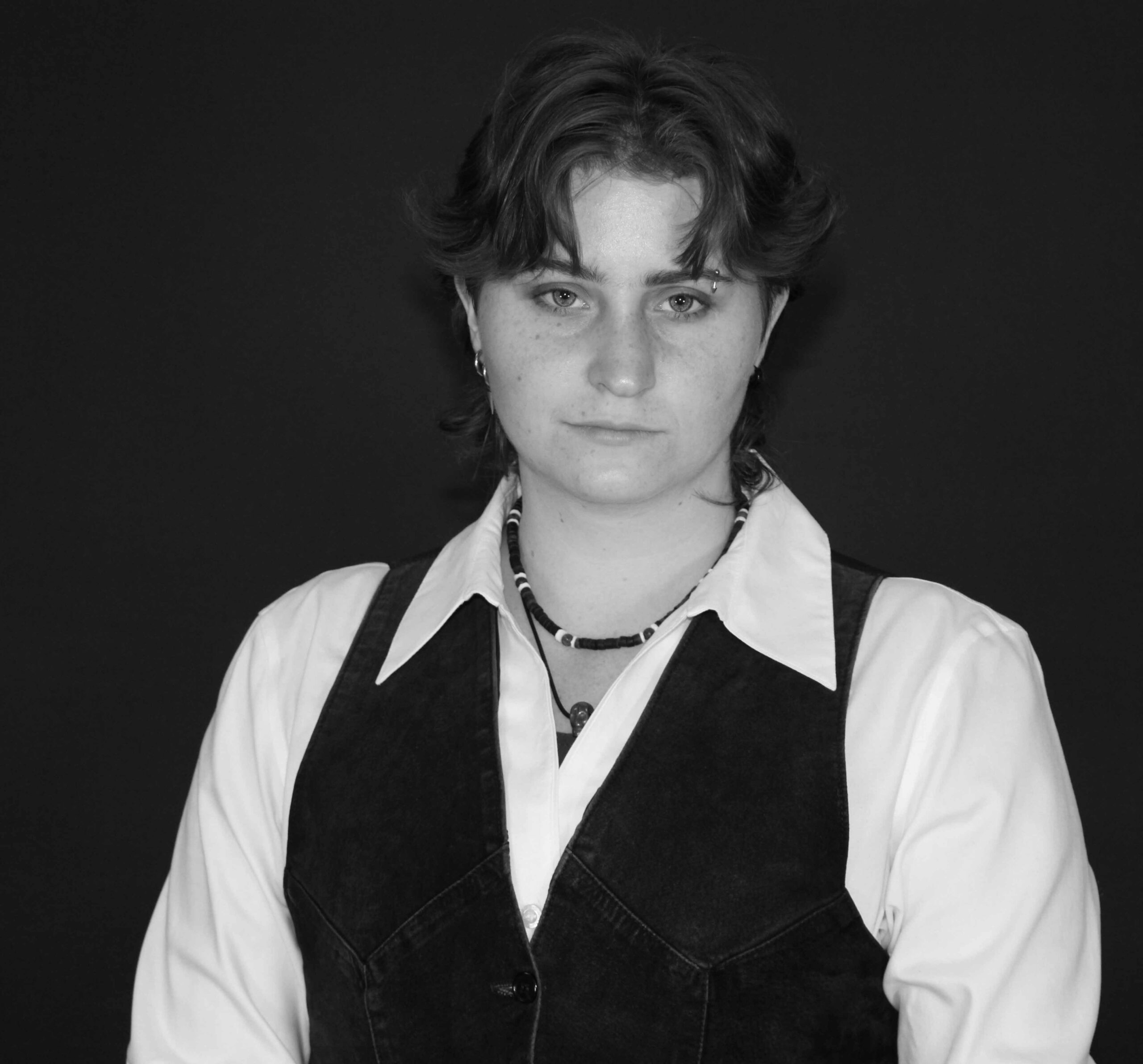 A Black and white photo of Gabby Christian who is wearing a vest and long white collared shirt